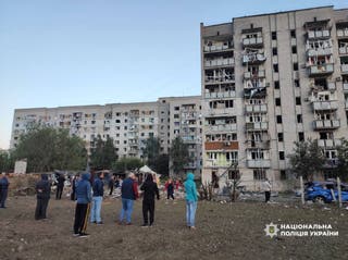 Residents stand in front of their apartment building damaged during Russian drone and missile strikes, amid Russia's attack on Ukraine, in the town of Smila, Cherkasy region